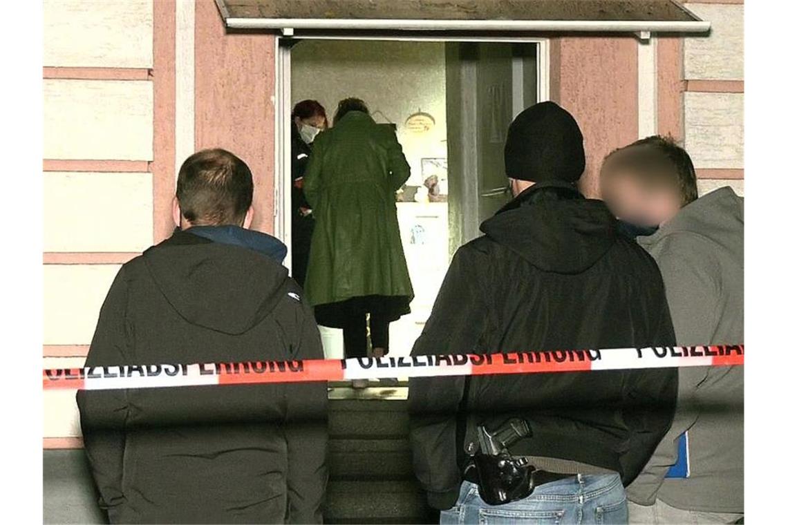 Polizisten stehen nach dem Stichwaffen-Angriff vor einem Mehrfamilienhaus, während drinnen Spuren gesichert werden. Foto: -/WTVnews/dpa