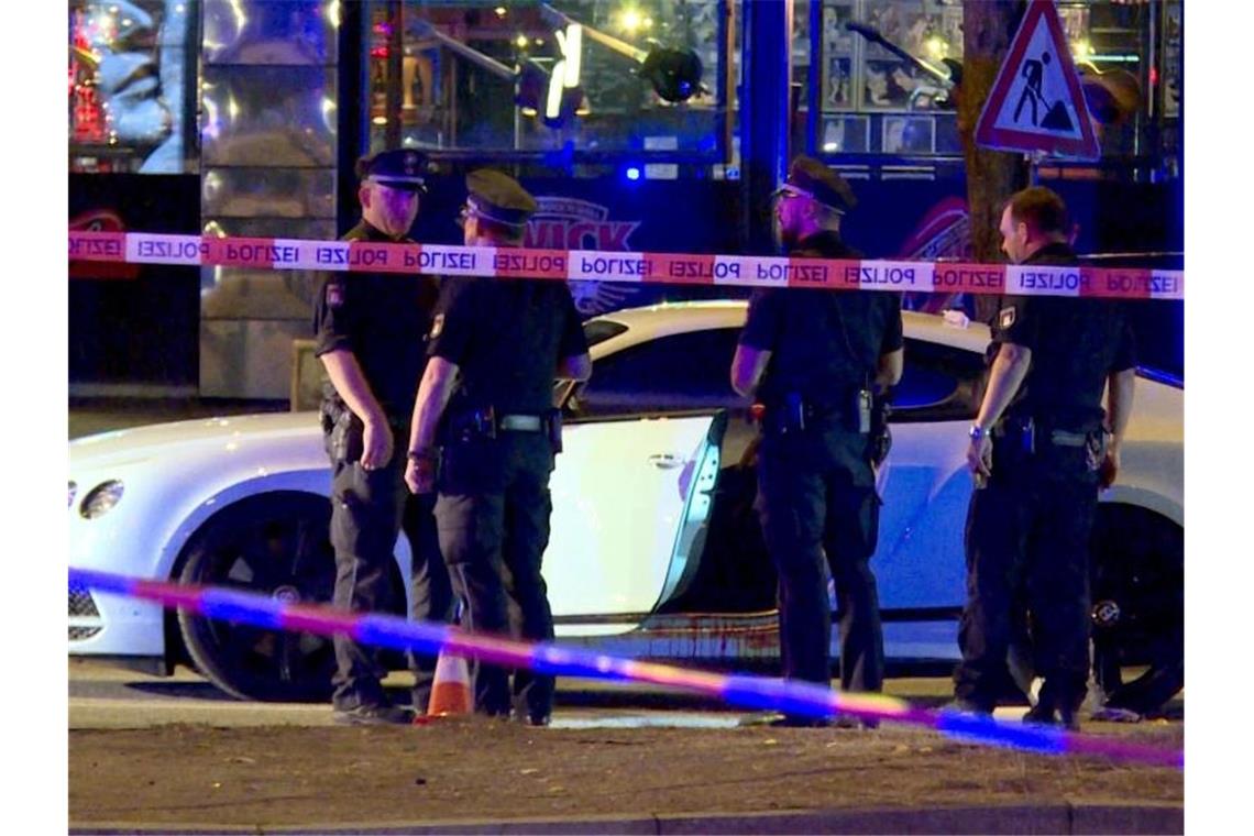 Polizisten stehen neben dem Auto des Rockerbosses auf dem Millerntorplatz an der Reeperbahn, nachdem die Schüsse gefallen waren. Foto: Mücahid Güler/dpa