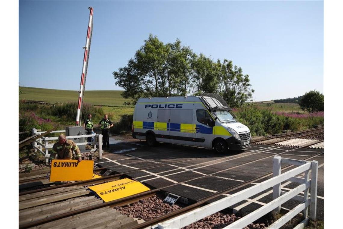 Nach heftigem Regen: Drei Tote bei Zugunglück in Schottland Polizisten stehen neben einem Polizeifahrzeug in der Nähe der Unglücksstelle. Foto: Jane Barlow/PA Wire/dpa