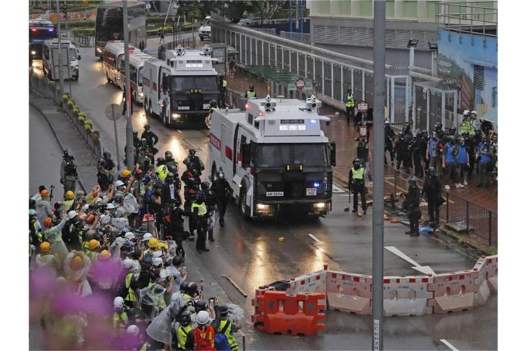 Polizisten stehen neben einem Wasserwerfer. Foto: Kin Cheung/AP