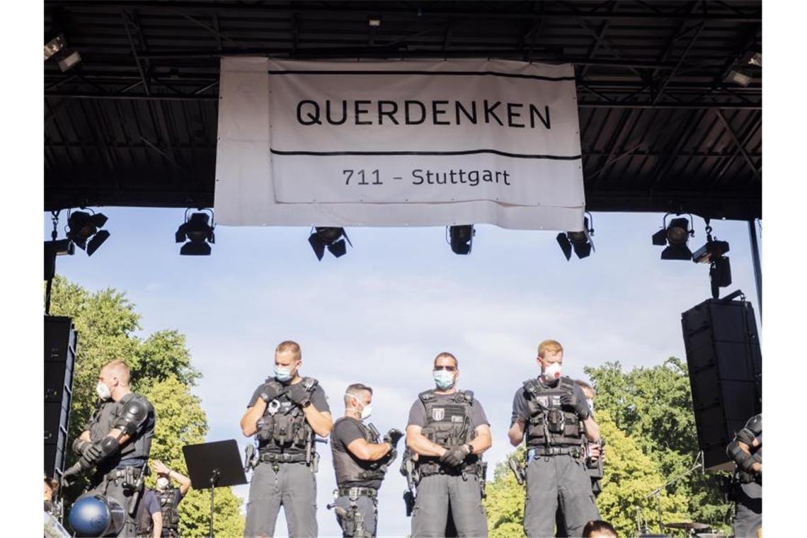 Streit um „Querdenken“: Unternehmen sieht Rechte verletzt Polizisten stehen unter einem Banner der Initiative „Querdenken 711“. Foto: Christoph Soeder/dpa/Archivbild