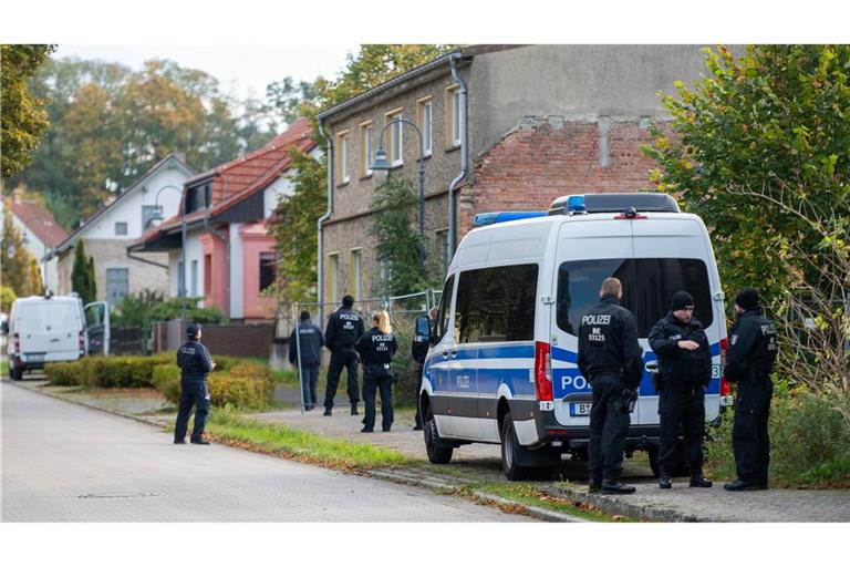 Polizisten stehen vor einem Grundstück in Tauche.