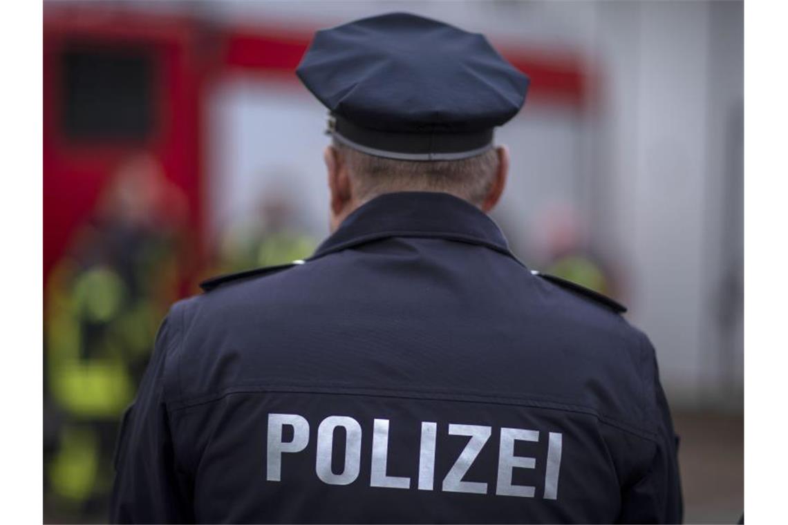 Polizisten stehen vor einem Polizeifahrzeug. Foto: Jens Büttner/Archivbild