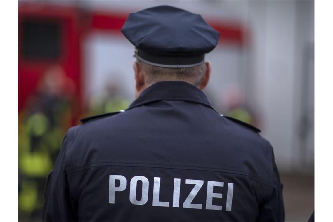 Maskierter Mann in Supermarkt: Angestellte verletzt Polizisten stehen vor einem Polizeifahrzeug. Foto: Jens Büttner/zb/dpa