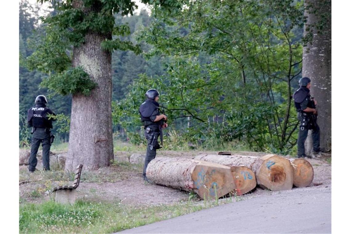 Polizisten stehen vor einem Waldstück an einer Straße bei Oppenau. Am Vortag hatte ein Mann bei einer Kontrolle Polizisten bedroht und entwaffnet. Foto: Sven Kohls/SDMG/dpa