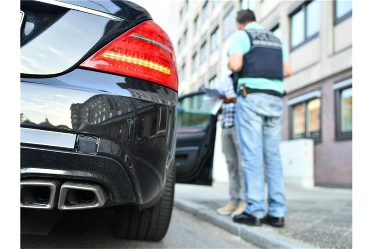 Polizisten stehen während einer Kontrolle an einem Fahrzeug. Foto: Uwe Anspach/dpa/Symbolbild