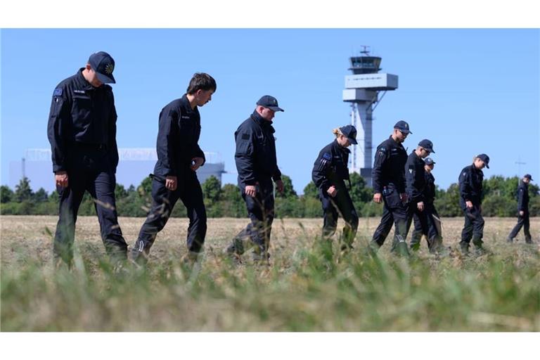 Polizisten suchen nach dem Vorfall am Flughafen Leipzig/Halle die Umgebung ab. Auf einem angrenzenden Feld wurden sie offenbar fündig.
