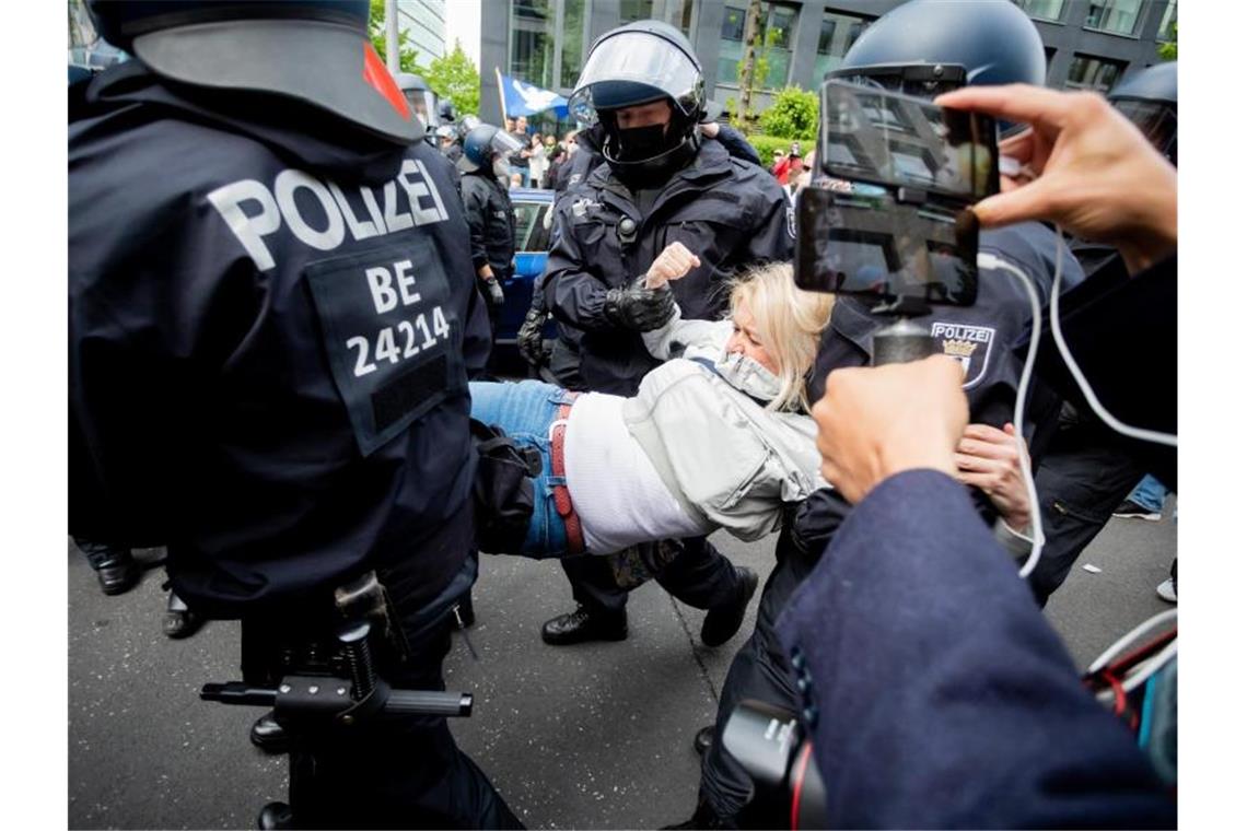 Trotz Demo-Verboten: Kleinere Corona-Proteste in Berlin Polizisten tragen eine Frau von einer Kundgebung weg. Foto: Christoph Soeder/dpa