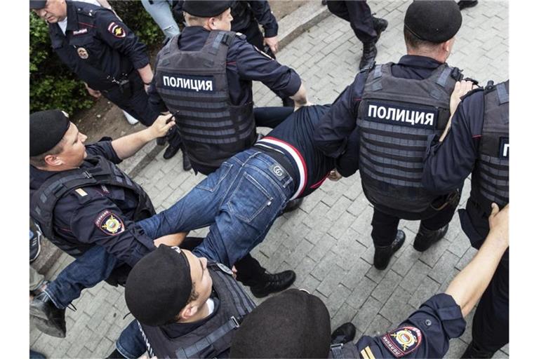 Polizisten tragen einen festgenommenen Demonstranten weg. Mehr als 200 Menschen sind in Moskau festgenommen worden. Foto: Pavel Golovkin/AP
