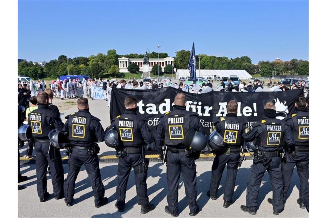 Polizisten umstellen auf der Theresienwiese einen Demonstrationszug. Foto: Peter Kneffel/dpa
