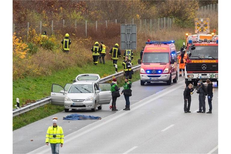 Polizisten und Rettungskräfte stehen neben dem Leichnam der jungen Frau auf der Autobahn 7. Foto: Benjamin Nolte/dpa