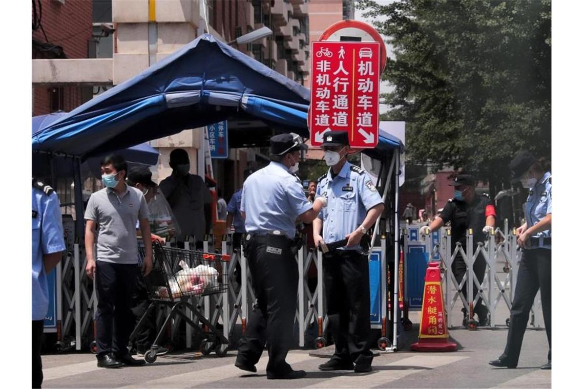 Corona-Ausbruch: Peking wird teilweise abgeriegelt Polizisten und Sicherheitsbeamte vor abgeriegelten Wohngebäuden in der chinesischen Hauptstadt. Foto: Andy Wong/AP/dpa