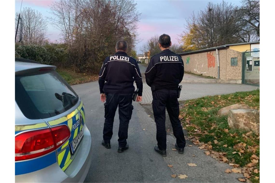 Polizisten vor dem Bereich eines Tatorts in einem Garagenkomplex, in dem die tote 14-Jährige gefunden worden ist. Foto: Thomas Schulz/dpa