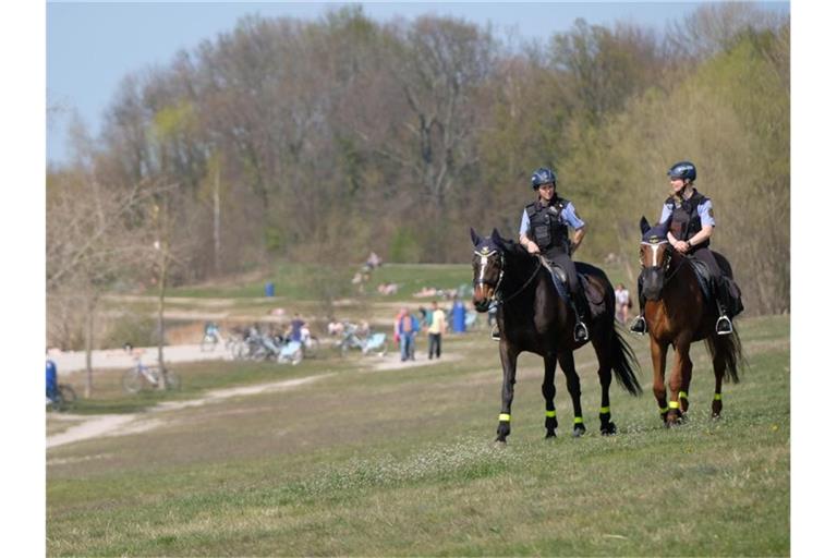 Polizistinnen der Reiterstaffel sind am Ufer des Cospudener Sees südlich von Leipzig auf Streife. Die Menschen in Deutschland haben sich auch am Ostersonntag weitgehend an die Einschränkungen gehalten. Foto: Sebastian Willnow/dpa-Zentralbild/dpa