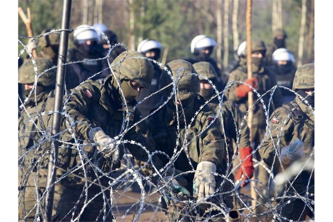 Migration via Belarus - Neue Sanktionen nahen Polnische Polizisten und Grenzschützer stehen in Grodno am Stacheldrahtzaun. Foto: Leonid Shcheglov/BelTA/dpa