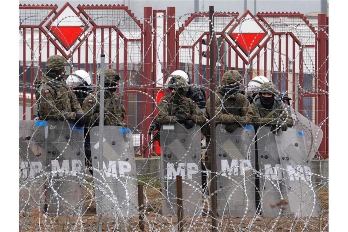 Polens Grenzschutz: Noch etwa 10.000 Migranten in Belarus Polnische Sicherheitskräfte stehen hinter dem Grenzzaun am Grenzübergang Brusgi (Belarus) und Kuznica (Polen). Foto: Ulf Mauder/dpa