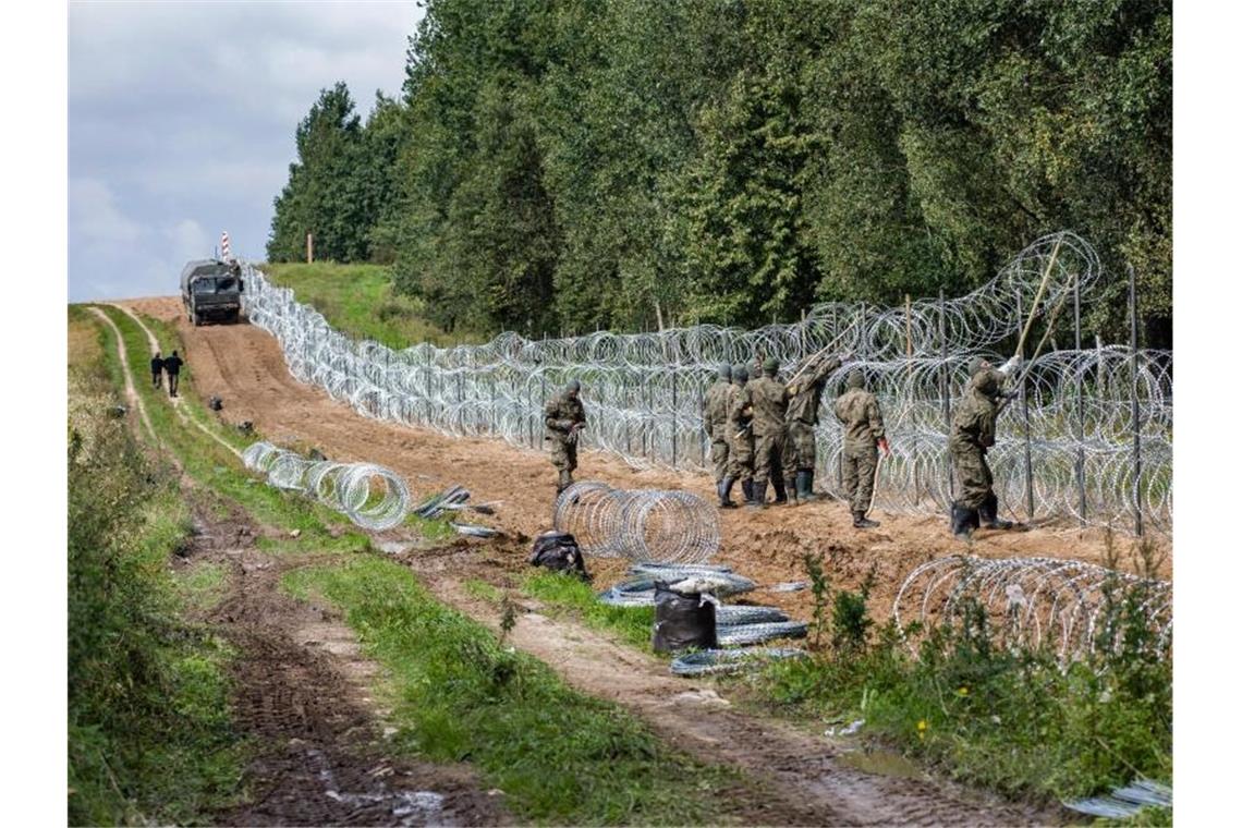 Polnische Soldaten errichten einen Stacheldrahtzaun Grenze zu Belarus (Archiv). Foto: Attila Husejnow/SOPA Images via ZUMA Press Wire/dpa