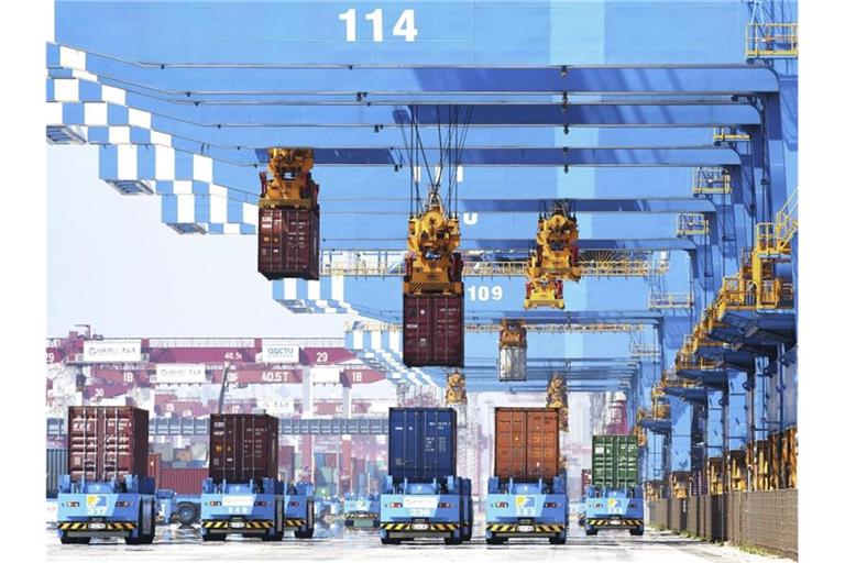 Portalkräne bewegen Container auf Transporter in einem Hafen in Qingdao in der ostchinesischen Provinz Shandong. Foto: Uncredited/CHINATOPIX/dpa