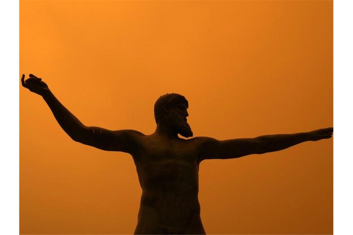 „Wir haben kein Wasser!“ - dramatische Szenen auf Euböa Poseidon von starkem Rauch umhüllt: eine Statue des griechischen Meeresgottes im Dorf Pefki auf der Insel Euböa. Foto: Petros Karadjias/AP/dpa