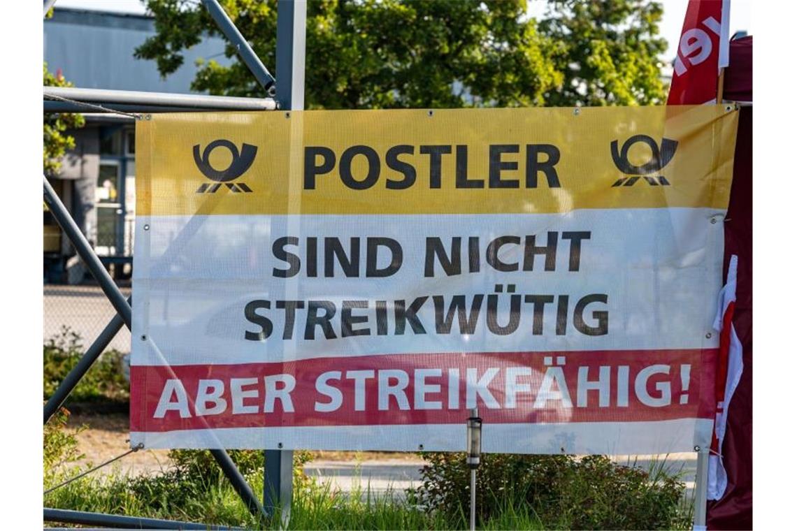„Postler - Sind nicht streikwütig aber streikfähig!“" steht auf einem Plakat vor dem Briefzentrum der Post in Straubing. Foto: Armin Weigel/dpa