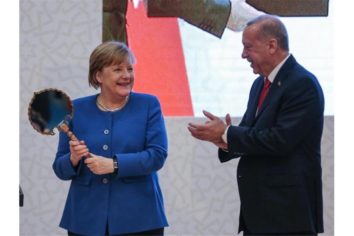 Merkel: Deutschland will Türkei in Flüchtlingspolitik helfen Präsident Erdogan überreicht der Kanzlerin einen Spiegel als Gastgeschenk. Foto: Ahmed Deeb/dpa