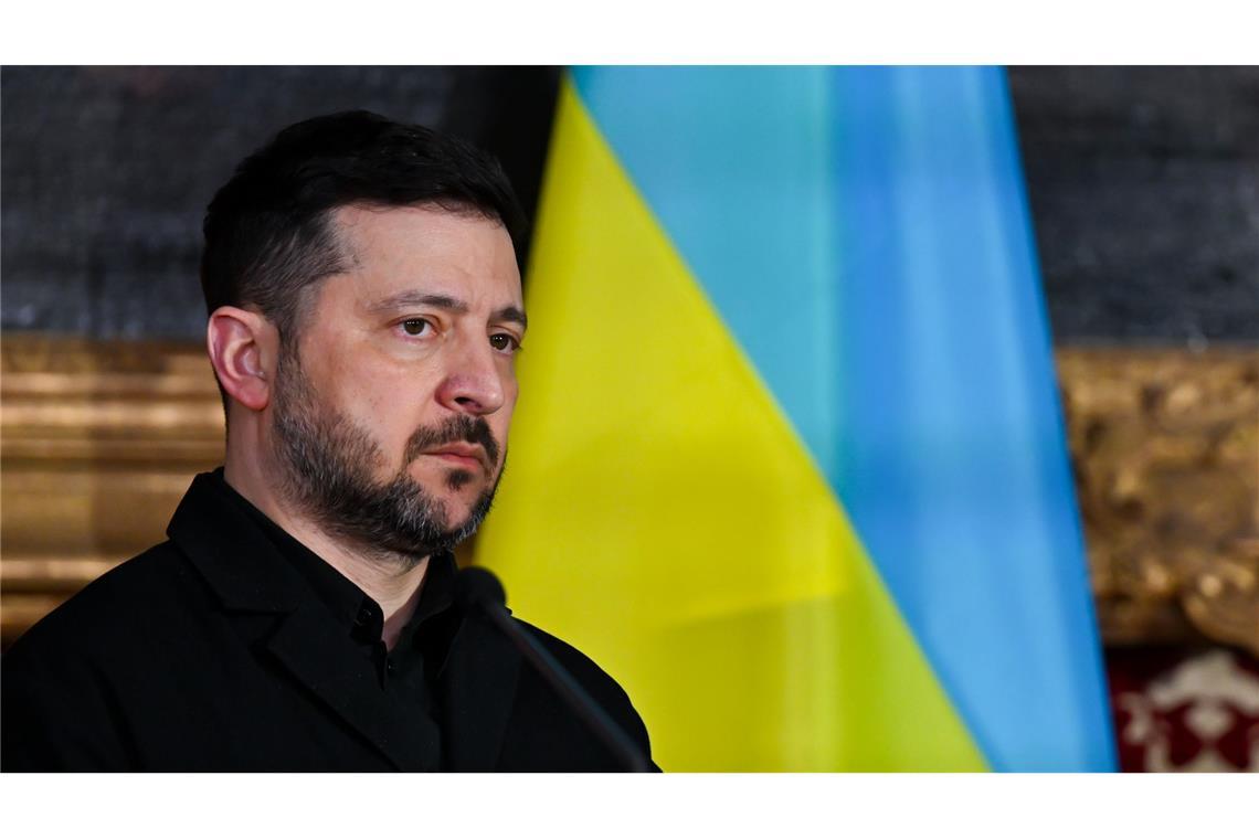 Präsident Wolodymyr Selenskyj steht vor einer ukrainischen Flagge.