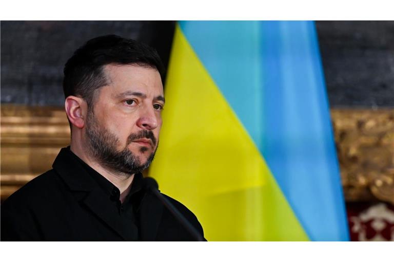 Präsident Wolodymyr Selenskyj steht vor einer ukrainischen Flagge.