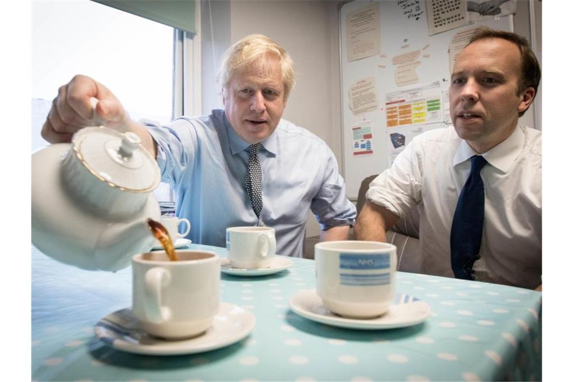 Brexit, Pubs, Gesundheit: Darüber diskutieren die Briten Premierminister Boris Johnson und Gesundheitsminister Matt Hancock widmen sich beim Besuch eines Krankenhauses einer britischen Tradition - dem Teetrinken. Foto: Stefan Rousseau/PA Wire/dpa