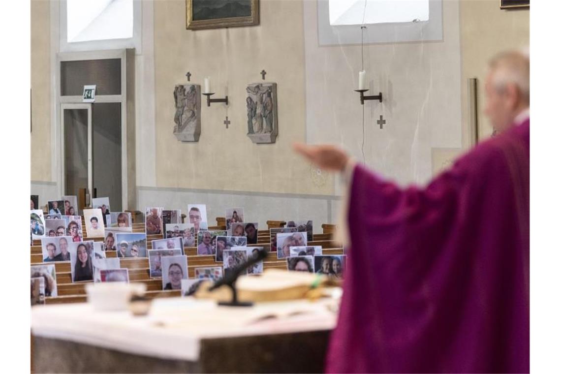 Gottesdienst im Livestream: Fotos der Gemeinde auf Bänken Priester Joachim Giesler steht in der Pfarrkirche vor Fotos mit Gemeindemitgliedern. Foto: Patrick Seeger/dpa
