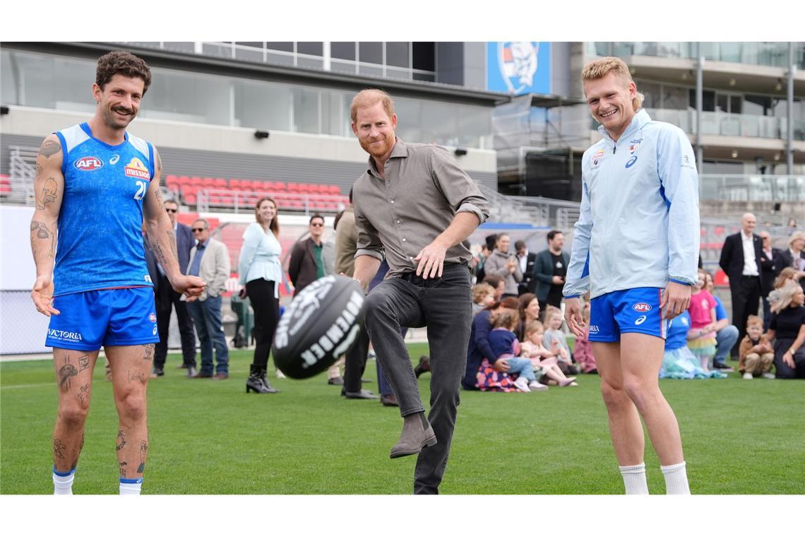 Prinz Harry (M), Herzog von Sussex, kickt einen Football.