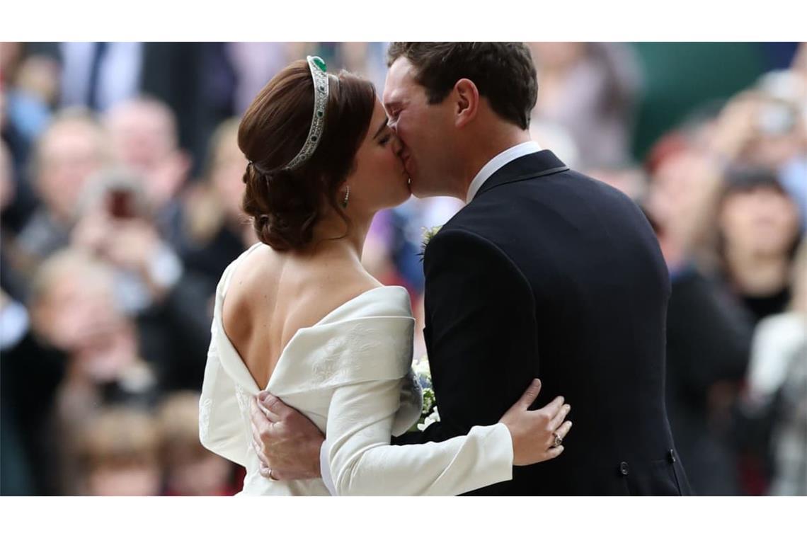 Prinzessin Eugenie und ihr Ehemann Jack Brooksbank küssen sich nach ihrer Hochzeit. Der tiefe Rückenausschnitt sorgte seinerzeit für Aufsehen, weil Eugenie damit eine Narbe am Rücken offen zeigte.