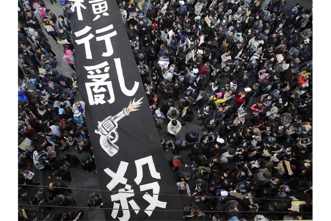 Pro-demokratische Demonstranten marschieren unter einem Banner mit der Aufschrift „Um sich greifendes Töten“ steht. Foto: Kin Cheung/AP/dpa