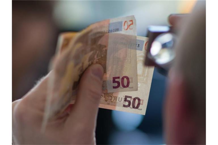 Prüfender Blick: Wegen den Corona-Einschränkungen ist weniger Falschgeld im Umlauf. Foto: Andreas Arnold/dpa/Illustration