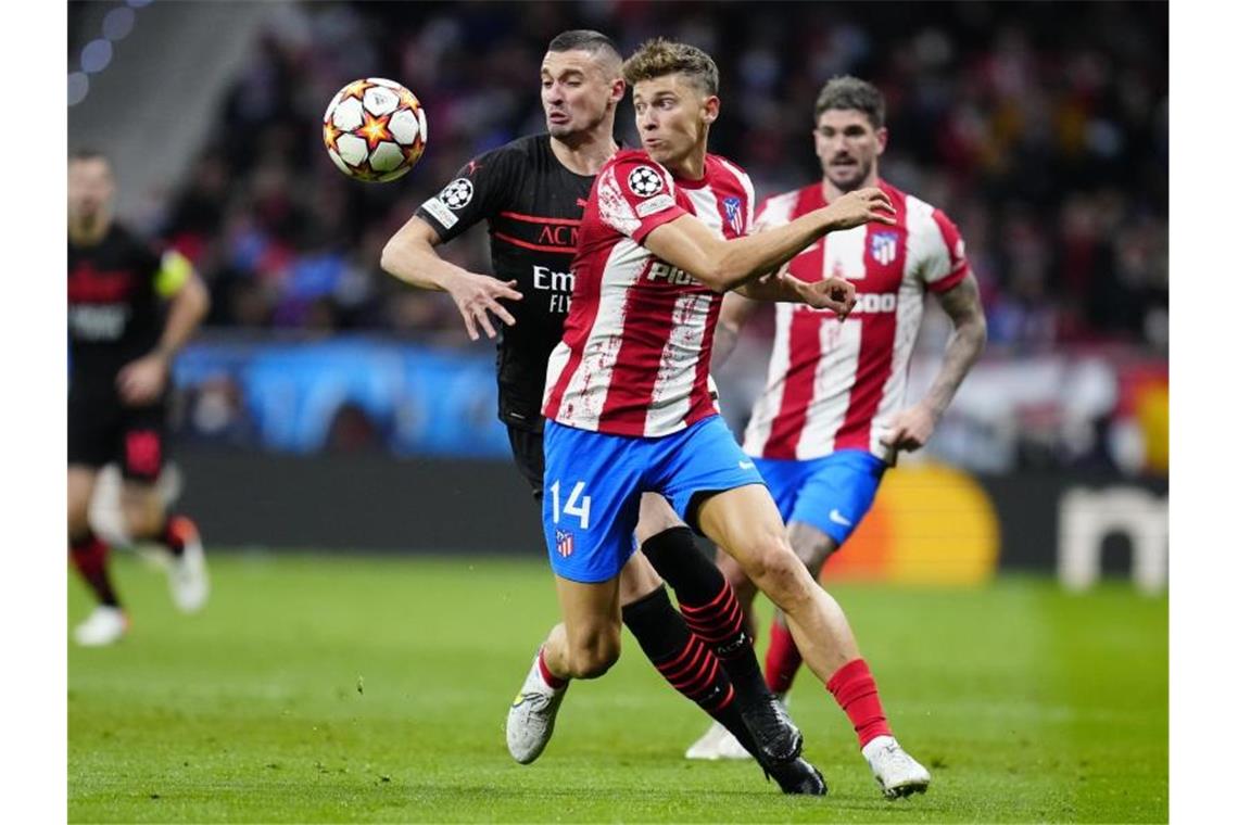 Rade Krunic (l, hinten) vom AC Mailand und Marcos Llorente (M,vorn) von Atletico Madrid kämpfen um den Ball. Foto: Manu Fernandez/AP/dpa