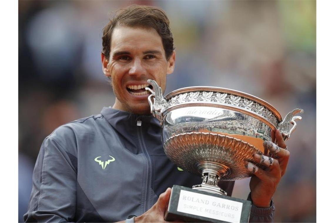 Rafael Nadal beißt nach seinem Sieg in die Trophäe. Foto: Christophe Ena/AP