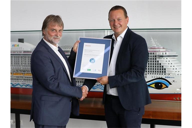 Ralf-Rainer Braun (l), Vorsitzender der Jury Umweltzeichen, überreicht Felix Eichhorn, Präsident von Aida Cruises, die Urkunde „Blauer Engel“. Foto: Bernd Wüstneck