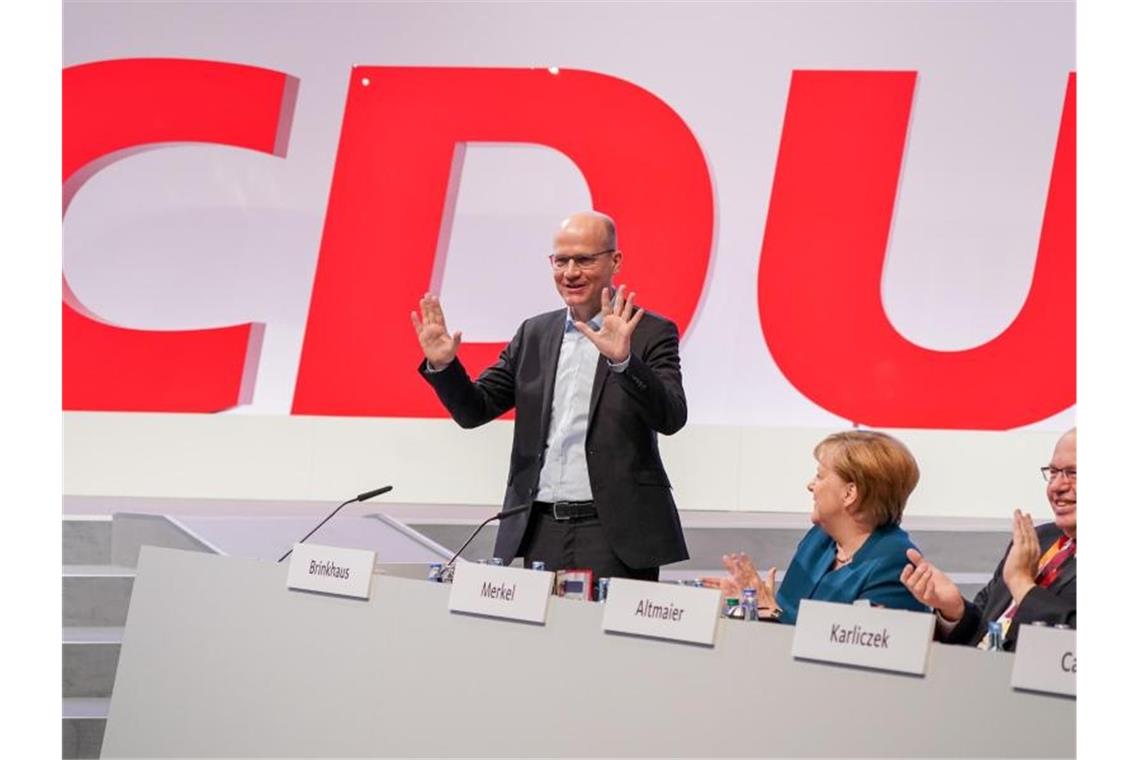 Parteitag in Leipzig: CDU räumt Streitfragen aus Ralph Brinkhaus, Fraktionsvorsitzender der CDU/CSU Fraktion im Bundestag, steht neben Kanzlerin Angela Merkel und Peter Altmaier, Bundesminister für Wirtschaft und Energie. Foto: Kay Nietfeld/dpa