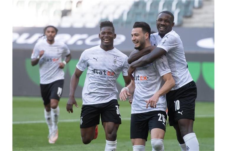 Ramy Bensebaini (2.v.l.) bejubelt sein Tor zum 3:0 gegen Bielefeld mit Marcus Thuram (r) und Breel Embolo. Gladbach siegt am Ende 5:0. Foto: Bernd Thissen/dpa