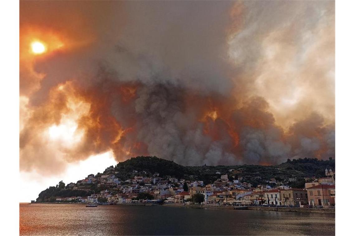 Waldbrände in Südeuropa toben weiter Rauch eines Waldbrandes steigt hinter einem Berghang in dem Ort Limni auf der Halbinsel Euböa etwa 160 Kilometer nördlich von Athen auf. Foto: Michael Pappas/AP/dpa