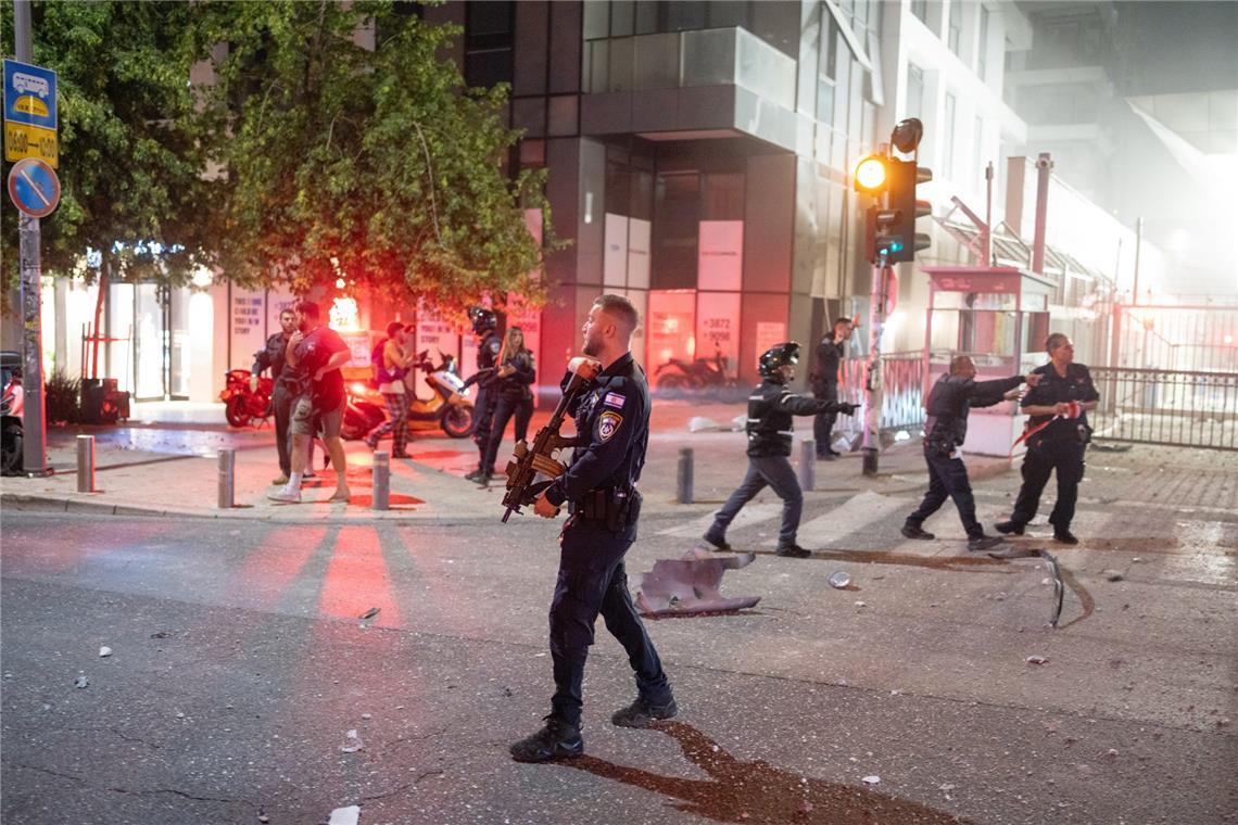 Rauch steigt auf, als israelische Polizeibeamte in Tel Aviv nach einem iranischen Raketenangriff durch die Straßen patrouillieren.