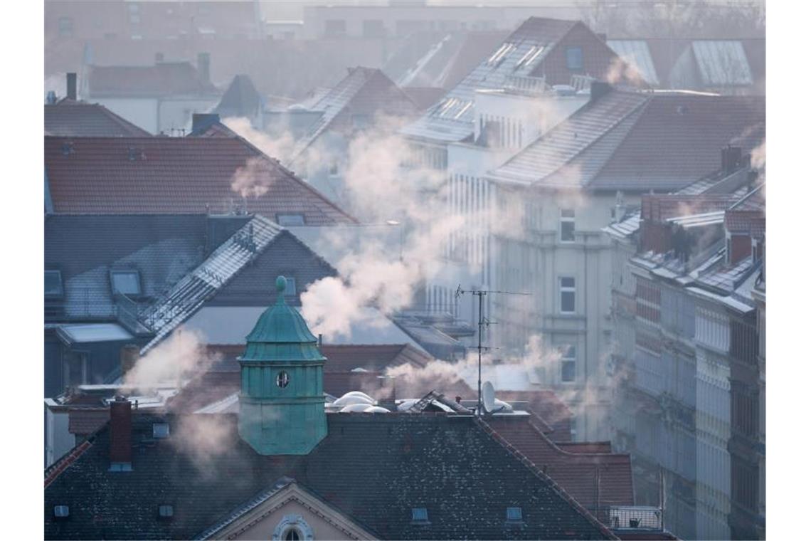 Rauch strömt aus den Kaminen auf den Dächern der Mehrfamilienhäuser im Leipziger Süden an einem kalten Wintermorgen. Foto: Jan Woitas/dpa-Zentralbild/dpa