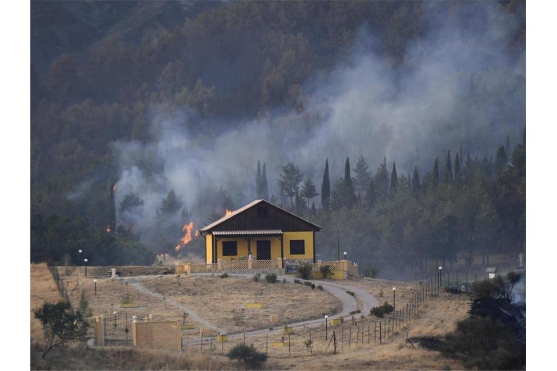 Rauch und Flammen hinter einem Haus nahe Petralia Soprana auf Sizilien. Foto: Salvatore Cavalli/AP/dpa