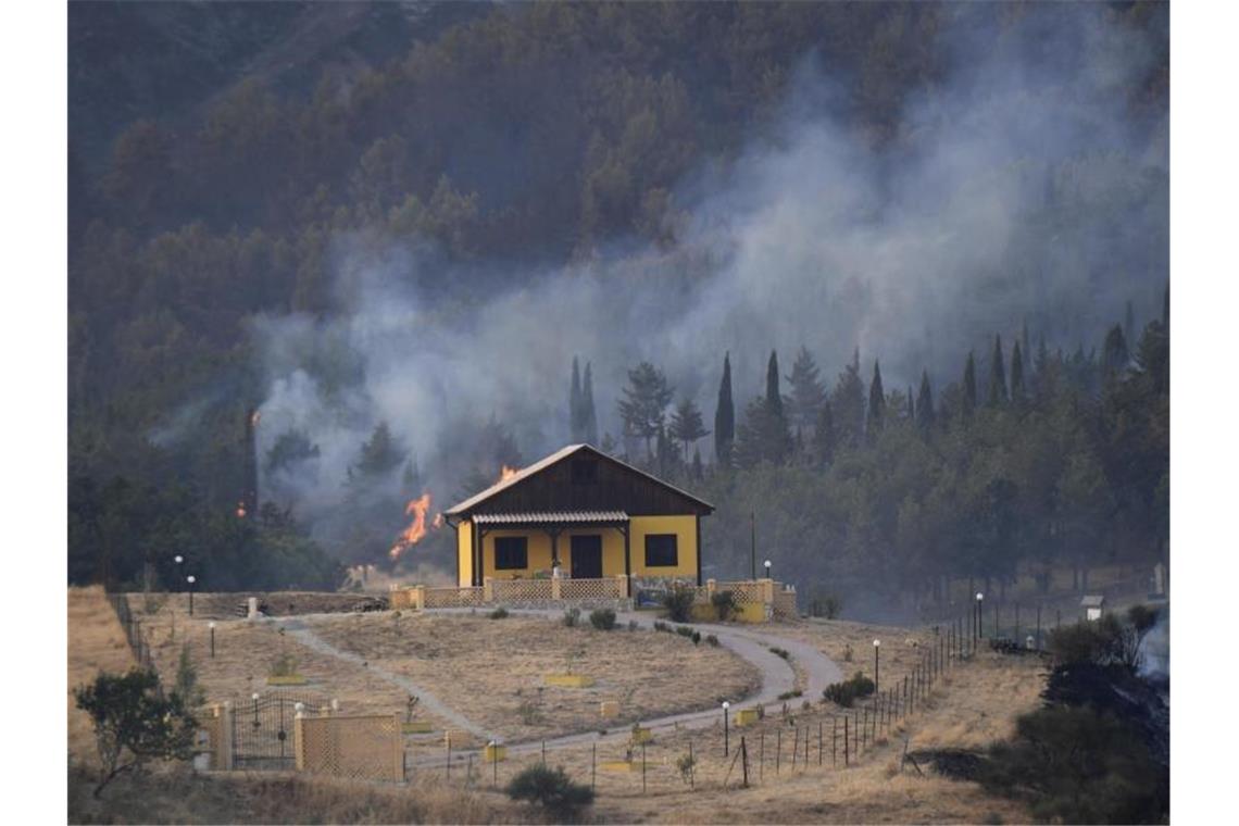 Leichte Besserung in Waldbrandgebieten Rauch und Flammen hinter einem Haus nahe Petralia Soprana auf Sizilien. Foto: Salvatore Cavalli/AP/dpa