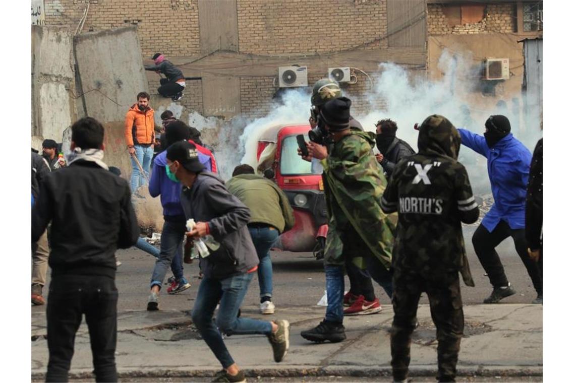 Rauch und Tränengas steigen bei Zusammenstößen zwischen Demonstranten und Sicherheitskräften in Bagdad auf. Foto: Hadi Mizban/AP/dpa