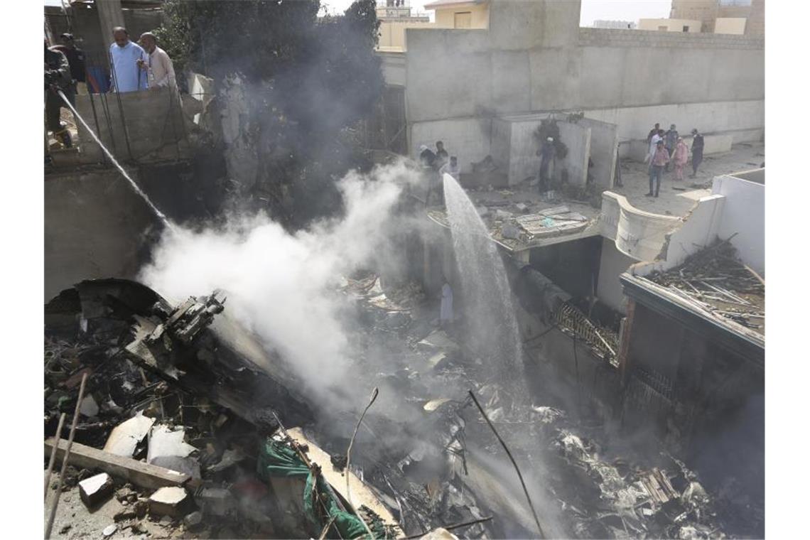Rauchende Trümmer am Ort des Unglücks in der Hafenstadt Karatschi. Foto: Fareed Khan/AP/dpa