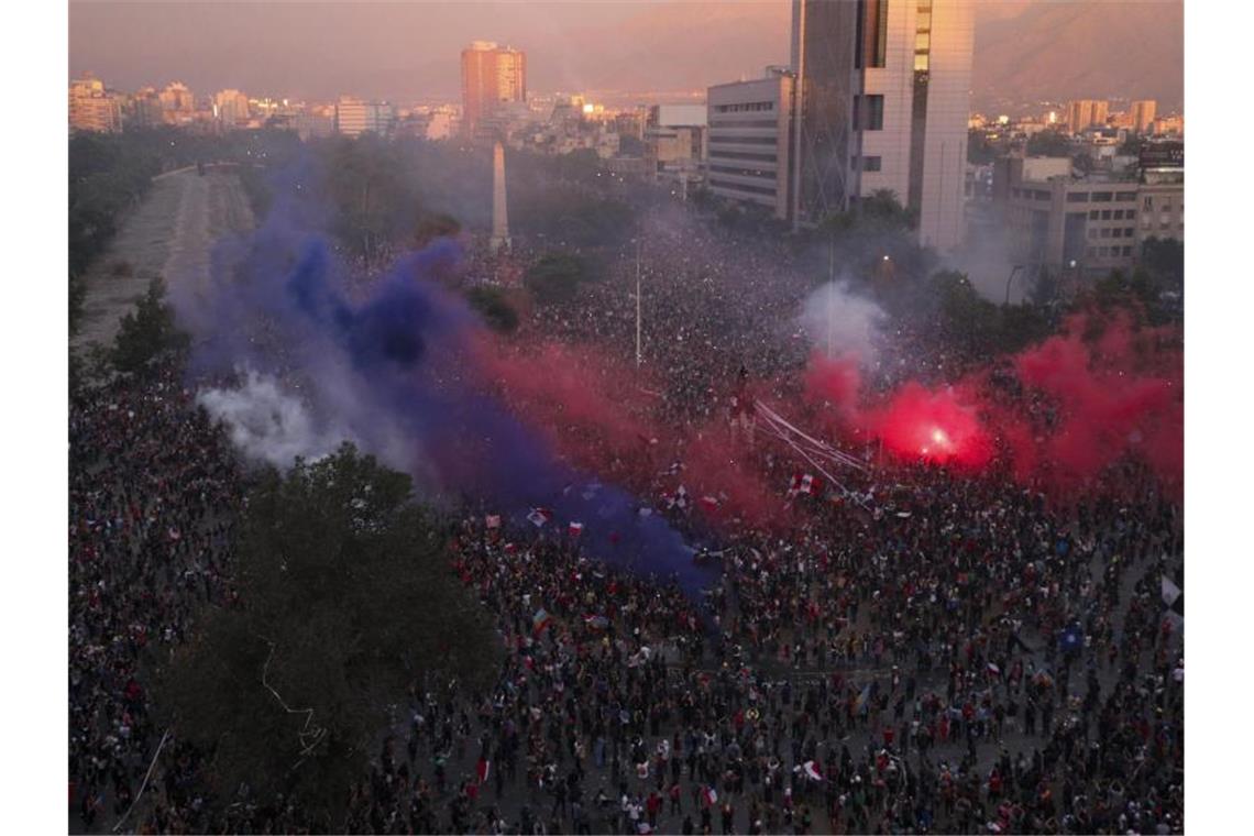 75.000 Chilenen protestieren gegen soziale Ungleichheit Rauchwolken von Fackeln steigen über einer riesigen Demonstration in Santiago de Chile auf. Foto: Esteban Felix/AP/dpa