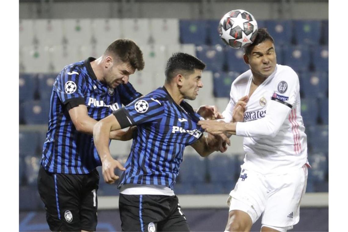 Real müht sich in Überzahl zu 1:0 in Bergamo Real Madrids Casemiro (r) köpft den Ball an Atalantas Cristian Romero (M) und Atalantas Berat Djimsiti vorbei. Foto: Luca Bruno/AP/dpa