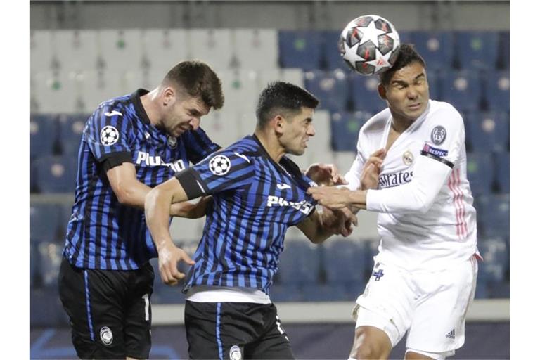 Real Madrids Casemiro (r) köpft den Ball an Atalantas Cristian Romero (M) und Atalantas Berat Djimsiti vorbei. Foto: Luca Bruno/AP/dpa