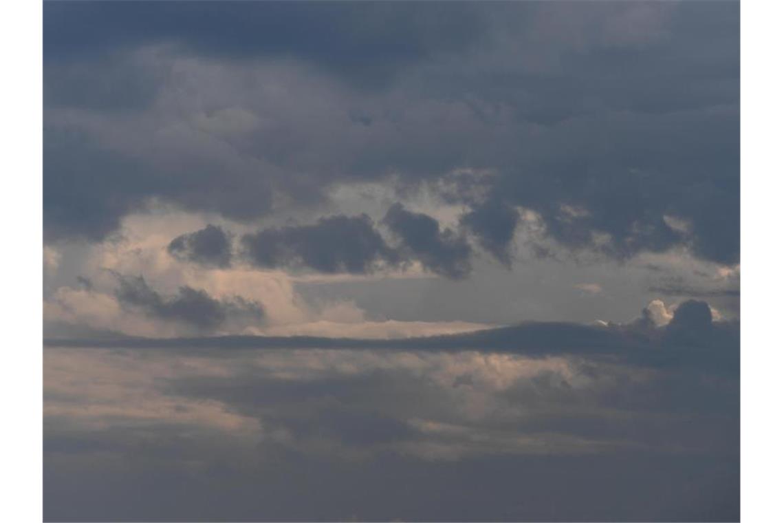 Regen Wolken verdrängen die Sonne am Himmel. Foto: Angelika Warmuth/dpa/Symbolbild