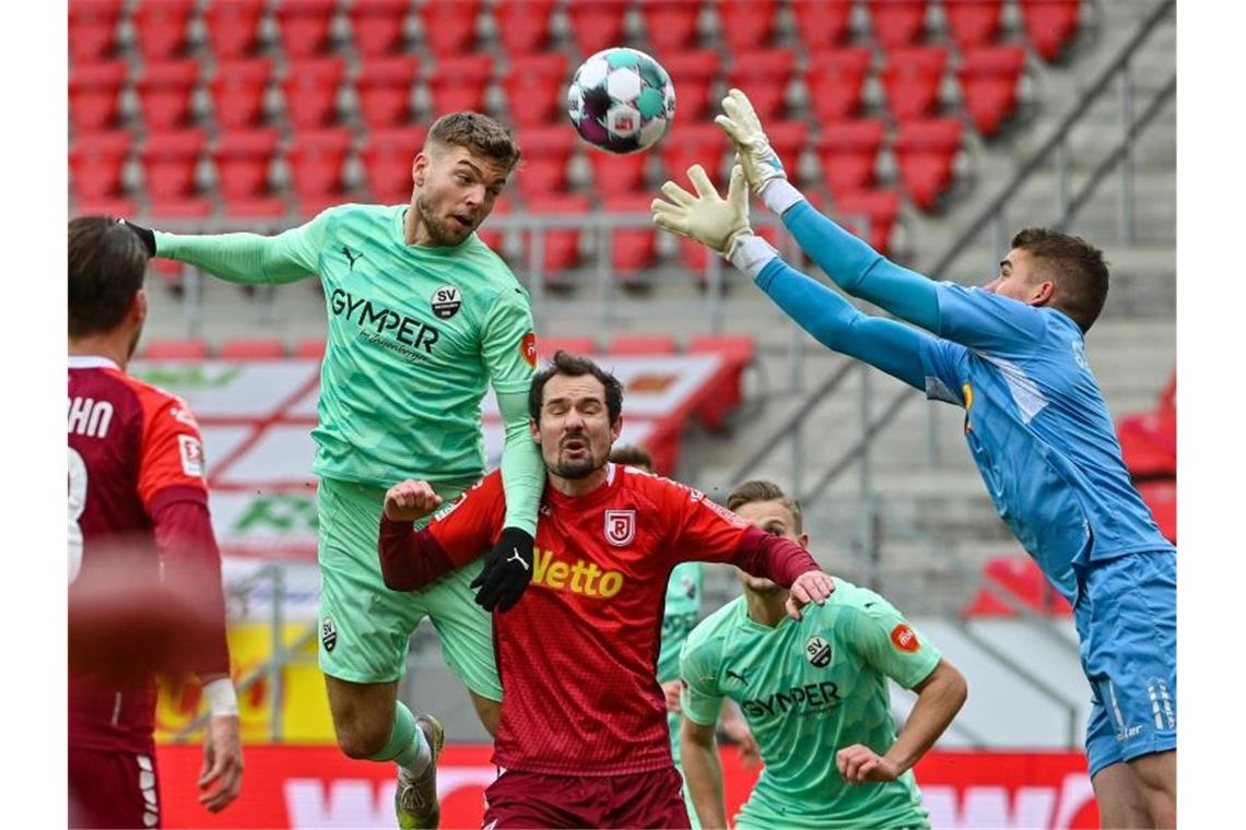 Regensburg-Torwart Alexander Meyer (r) kommt vor dem einköpfbereiten Sandhausener Alexander Esswein (l) an den Ball. Foto: Armin Weigel/dpa